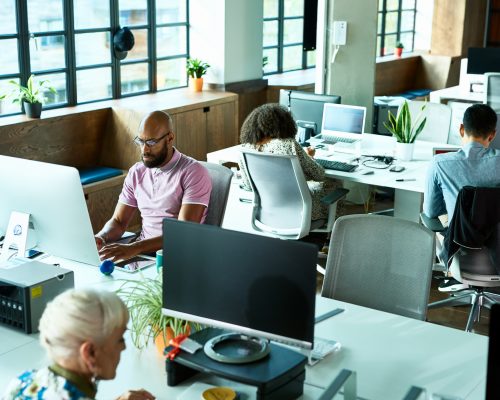 Businessmen and women using computers and concentrating, modern office environment, efficiency, productivity, corporate business