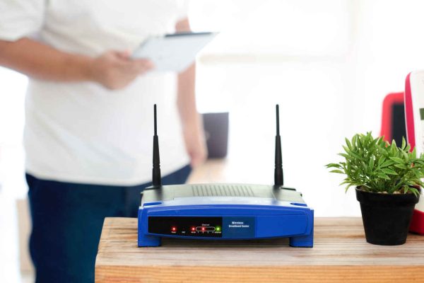 closeup of a wireless router and a young man using Tablet on living room at home